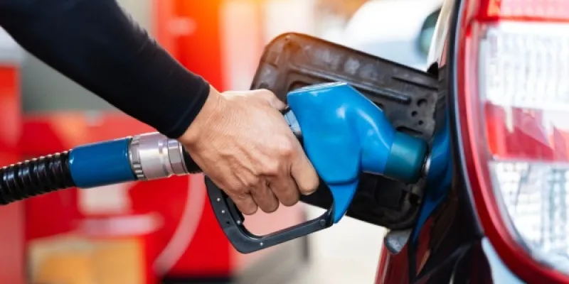 Mano de una persona echando gasolina barata a su coche
