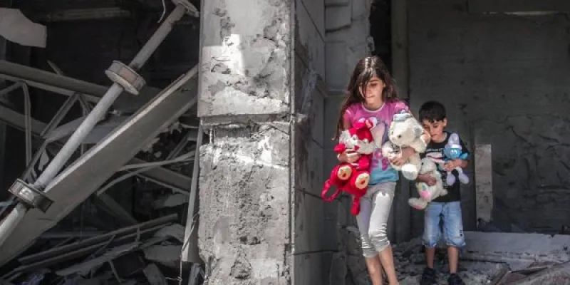 Niños palestinos recogiendo sus juguetes de su hogar destrozado en Gaza