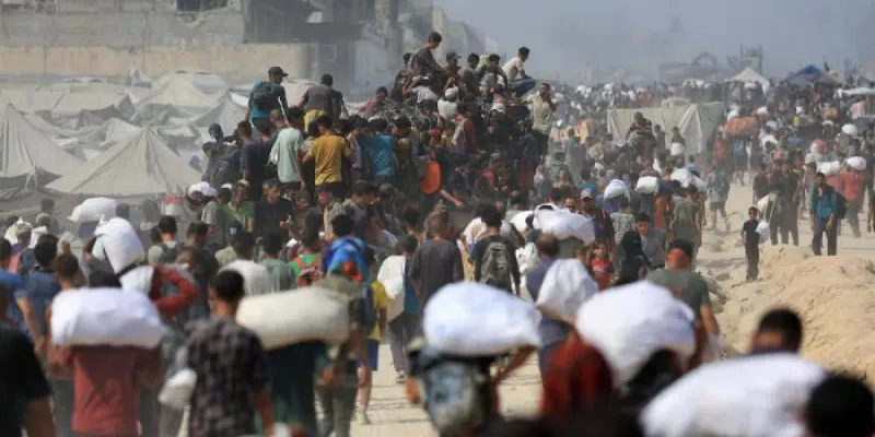 Cientos de ciudadanos palestinos transportan sacos con ayuda humanitaria 