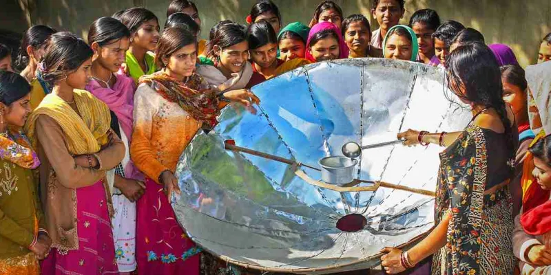 UNDP India / En la India, una mujer demuestra como cocinar con un reflector solar.