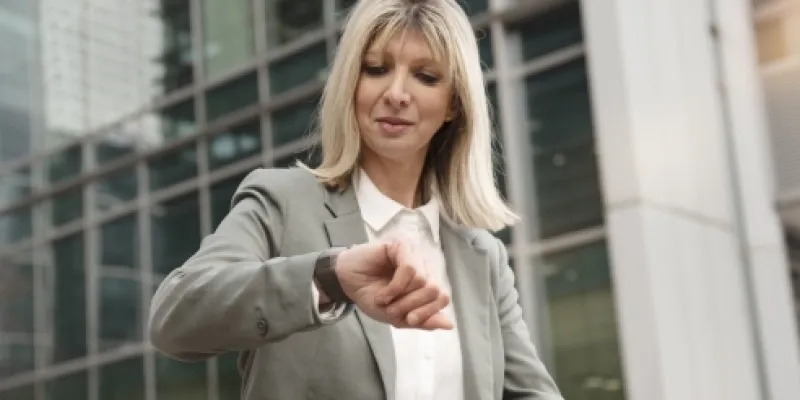 Mujer mirando el reloj a la hora de salir de la oficina