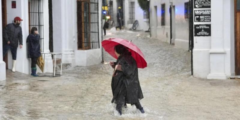 Una vecina de Grazalema (Cádiz) camina por una calle inundada debido a las intensas lluvias.