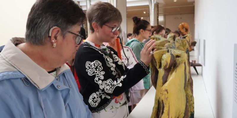 Una afiliada de la ONCE conoce, al tacto, una de las obras expuestas 