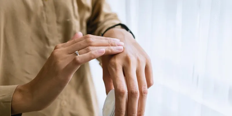 Mujer echándose crema en la mano
