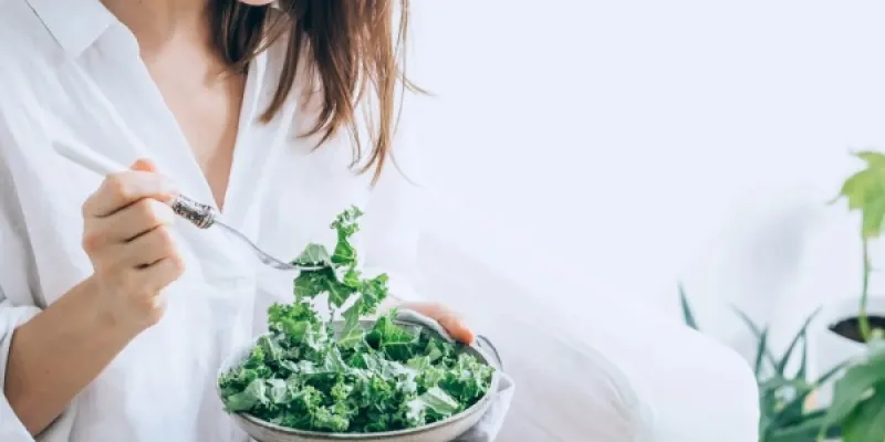 Una mujer comiendo vegetales. 