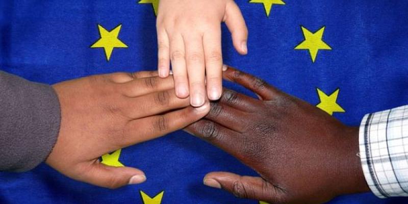 Manos de migrantes sobre la bandera de la UE