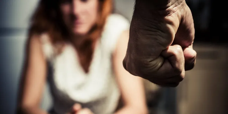 Mujer ante el puño amenazante de un hombre (iStock)
