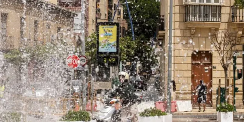 Chico en una moto frente a una fuente y  un termómetro que marca 34 grados
