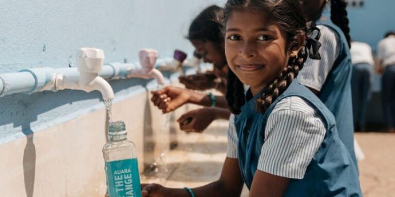 Niña llenando una botella de agua