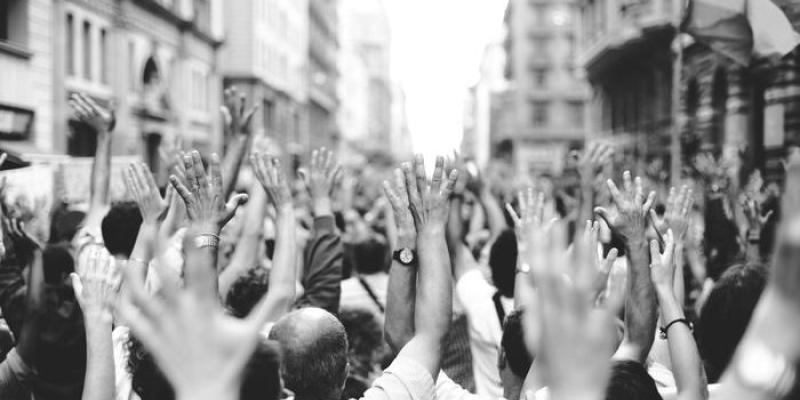 Fotografía en blanco y negro que muestra los brazos en alto de muchas personas en una manifestación