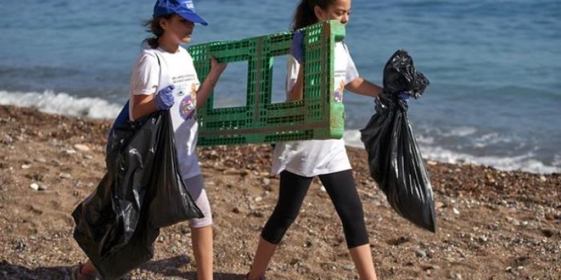 Dos jóvenes voluntarias retiran basuraleza en una playa 