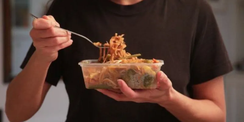 Una joven se alimenta de comida en envases de plástico