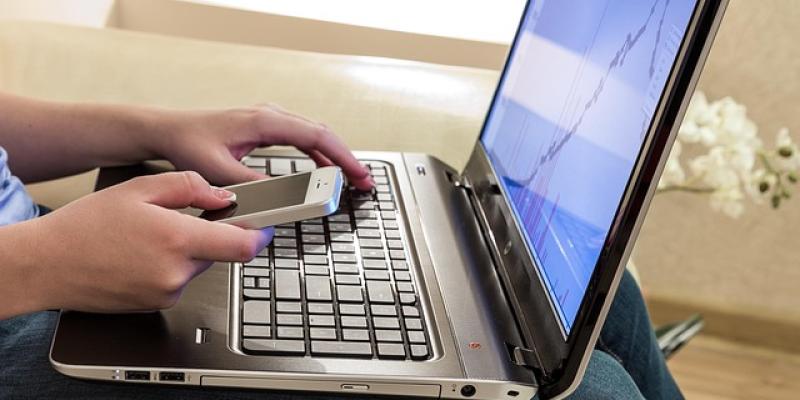 Manos de una persona en teletrabajo con su portátil y el móvil