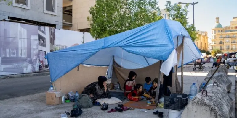 Una madre y sus hijos se refugian bajo una lona en Beirut tras verse obligados a abandonar su hogar.