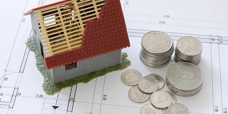 Imagen de una casa y monedas simbolizando el ahorro para comprar una vivienda
