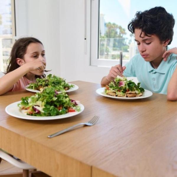 Dos menores comen comida vegetariana