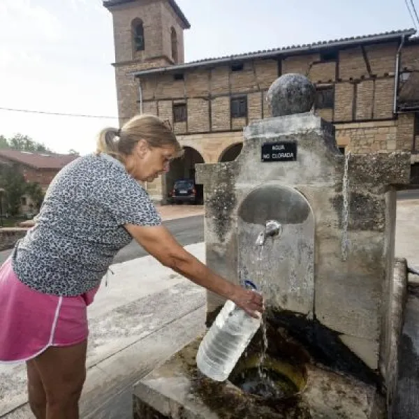Una vecina llena una garrafa en la fuente del pueblo, a la que tienen que acudir para beber de agua potable