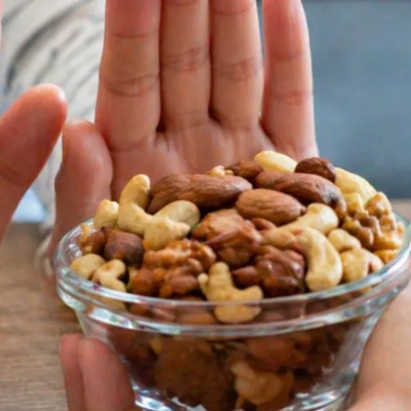 Manos de una persona apartando un bol de frutos secos