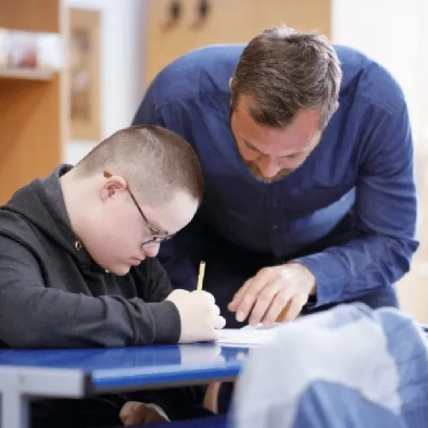 Un profesor atiende a un alumno con discapacidad