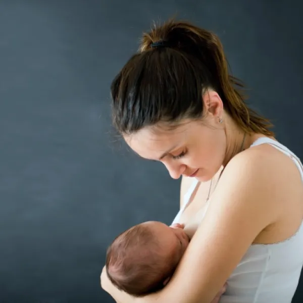 Una madre joven amamantando a su bebé recién nacido