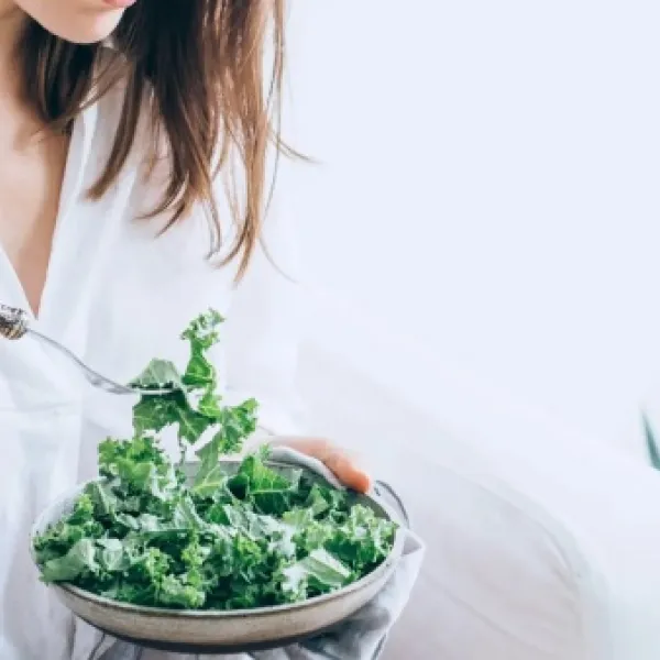 Una mujer comiendo vegetales.