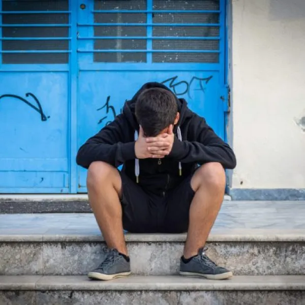 Un joven vulnerable, sentado en unas escaleras