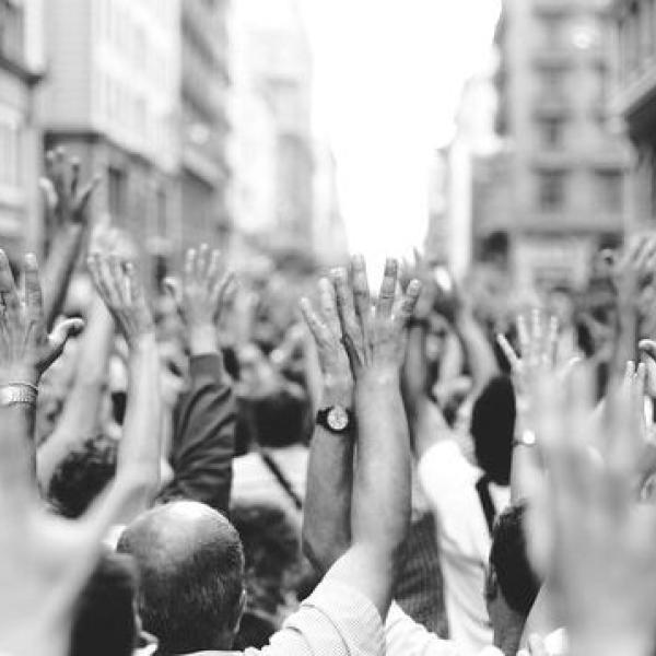 Fotografía en blanco y negro que muestra los brazos en alto de muchas personas en una manifestación