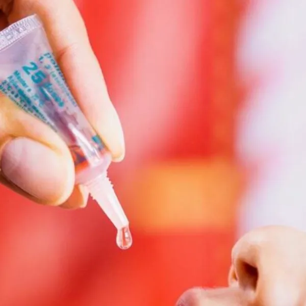 Mano de un médico administrando una vacuna oral a un niño