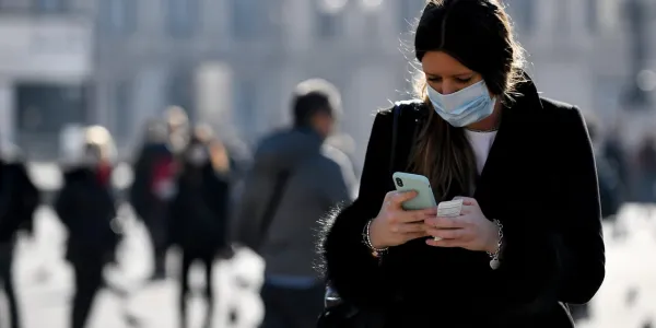 Mujer mirando un mensaje con mascarilla