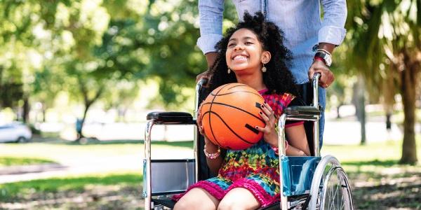 Niña en silla de ruedas jugando al baloncesto