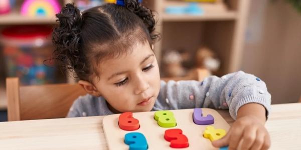 Niña en el colegio jugando con un puzzle de números encajables