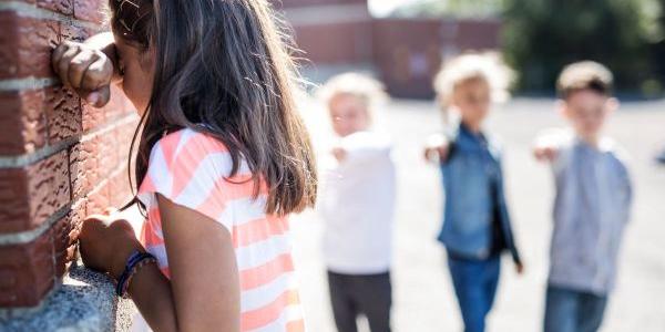 Varios niños señalan a una compañera en el patio del colegio 