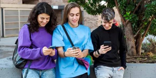 Varios adolescentes consultan sus móviles 