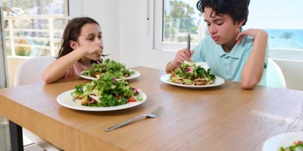 Dos menores comen comida vegetariana 