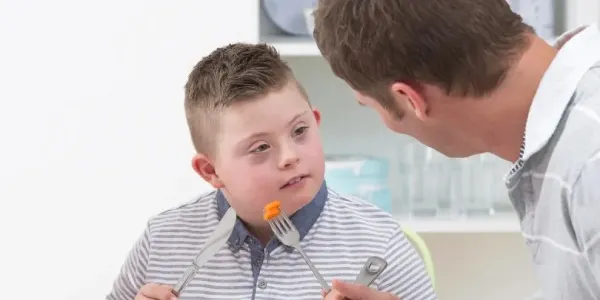 Un padre dando de comer a su hijo.