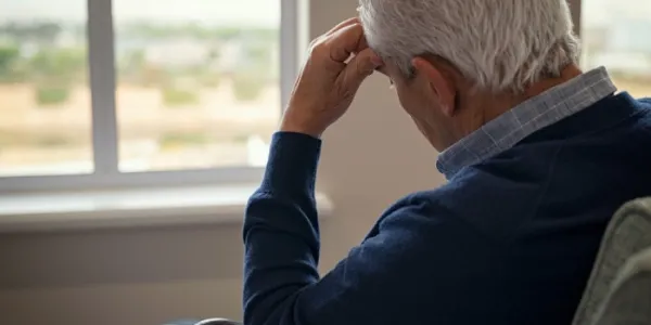 Un hombre con alzhéimer mira a una ventana 