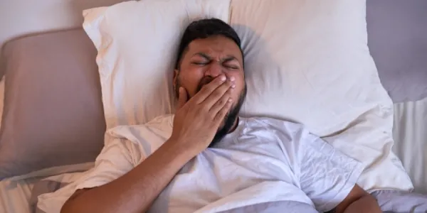 Un hombre bosteza mientras intenta dormir 