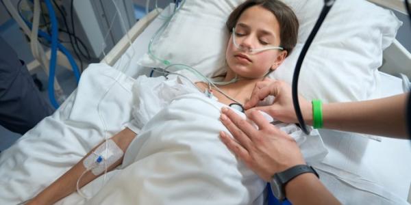 Una enfermera controla las constantes de una niña semiinconsciente 