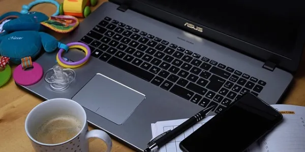 Un ordenador portátil, un móvil, café y juguetes infantiles