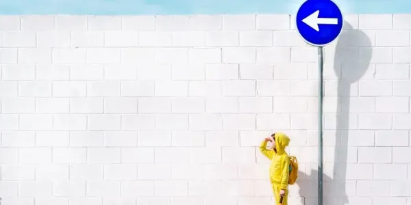 Niña vestida de amarillo frente a una señal azul luchando contra las barreras cognitivas