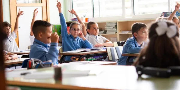 Estudiantes de primaria levantando la mano durante la lección en el aula