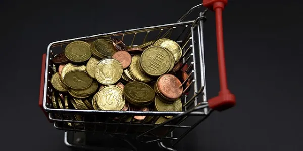 Carrito de la compra en miniatura lleno de monedas 