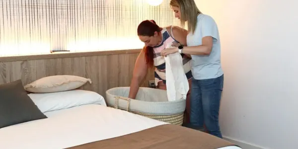 Foto de una madre acomodando la cuna de su hijo en una habitación de la Ciudad del Fútbol