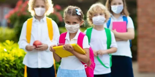 niños hablan en grupo con mascarilla en la puerta del colegio 