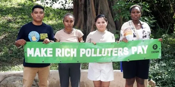 Activistas climáticos con una pancarta que pide gravar a los grandes contaminantes. 