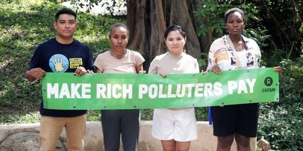 Activistas climáticos con una pancarta que pide gravar a los grandes contaminantes. 
