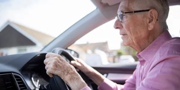 Persona mayor sentado ante el volante de un vehículo 