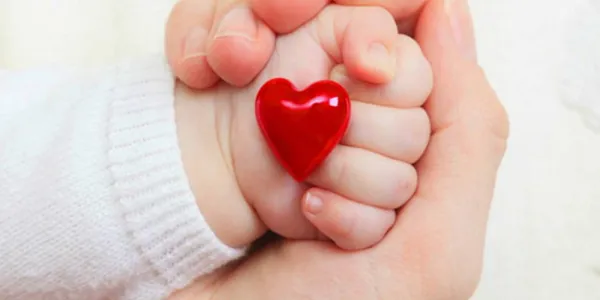 Mano de un bebé sosteniendo un corazón