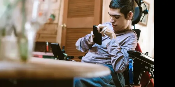 Un joven con discapacidad consultando su móvil.