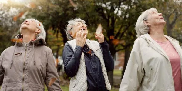 Tres mujeres mayores ríen en un parque forestal urbano 